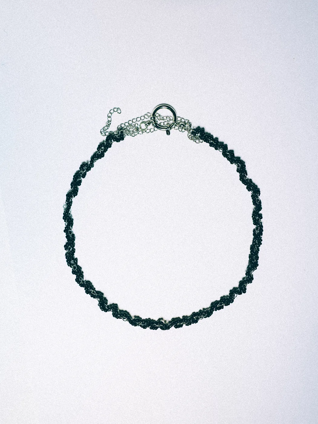 Black beaded necklace woven with a silver-tone chain
