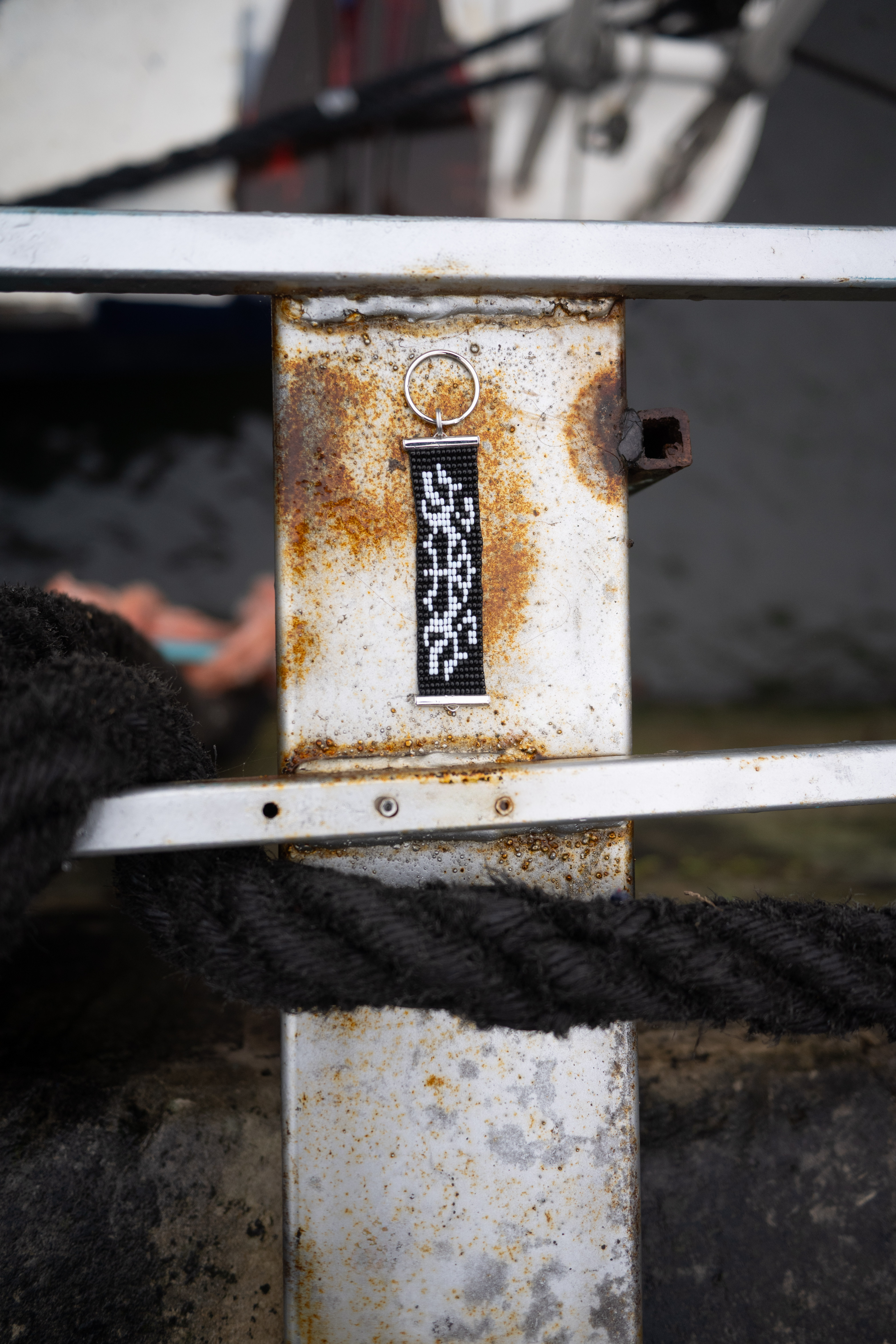 Black and white graphic beaded keyring photographed on rusted metal
